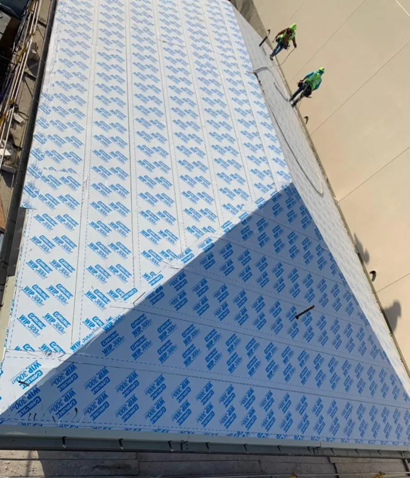 Professional roofers installing underlayment on a metal roof in Big Flats